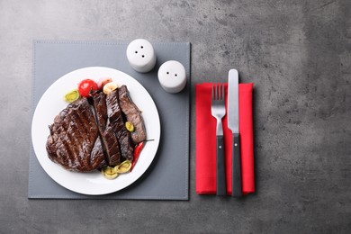 Delicious grilled beef meat served on grey table, flat lay