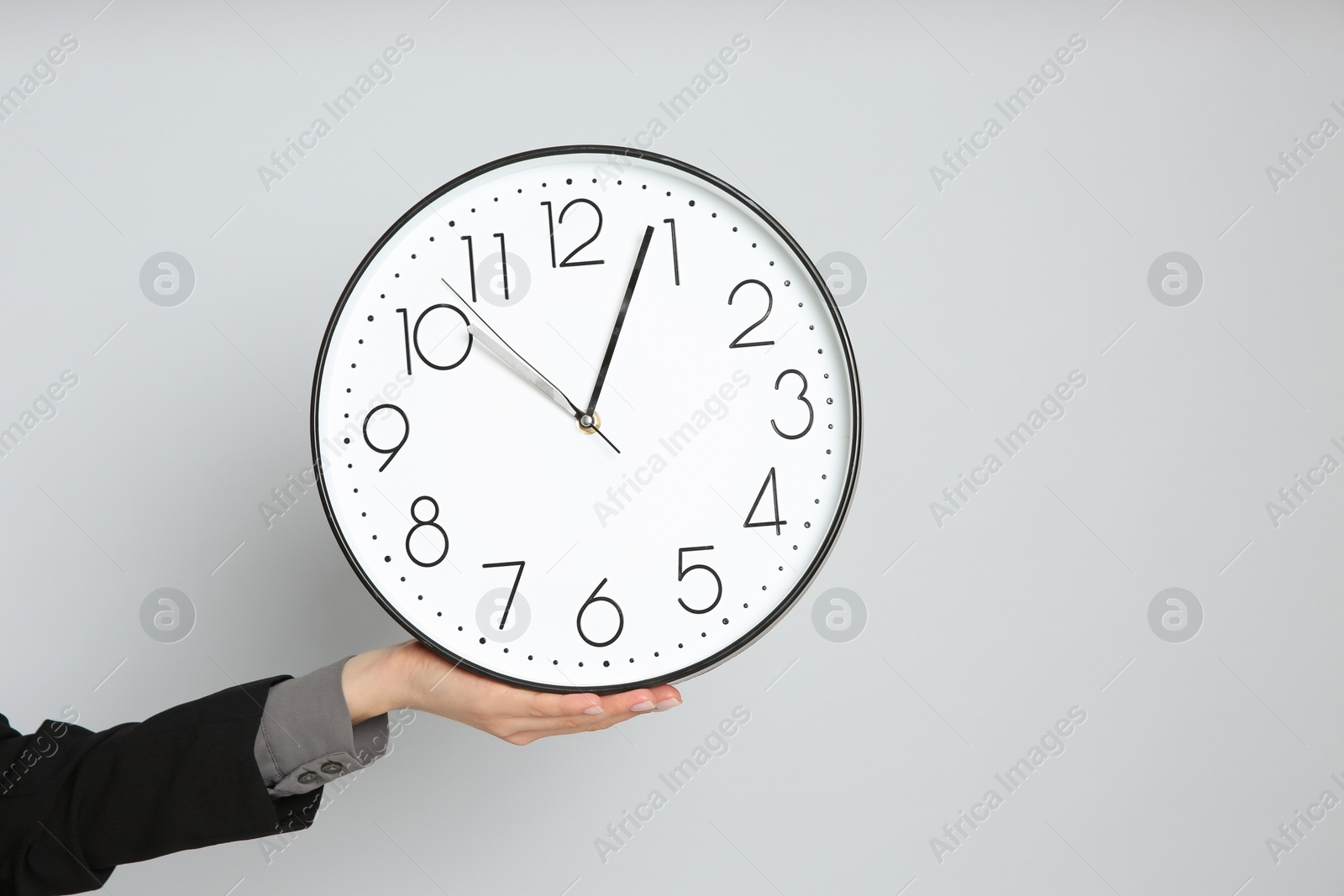 Photo of Businesswoman holding clock on light grey background, closeup with space for text. Time management