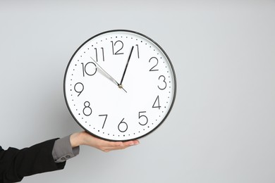 Photo of Businesswoman holding clock on light grey background, closeup with space for text. Time management