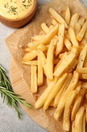 Photo of Delicious french fries served with sauce on grey textured table, flat lay