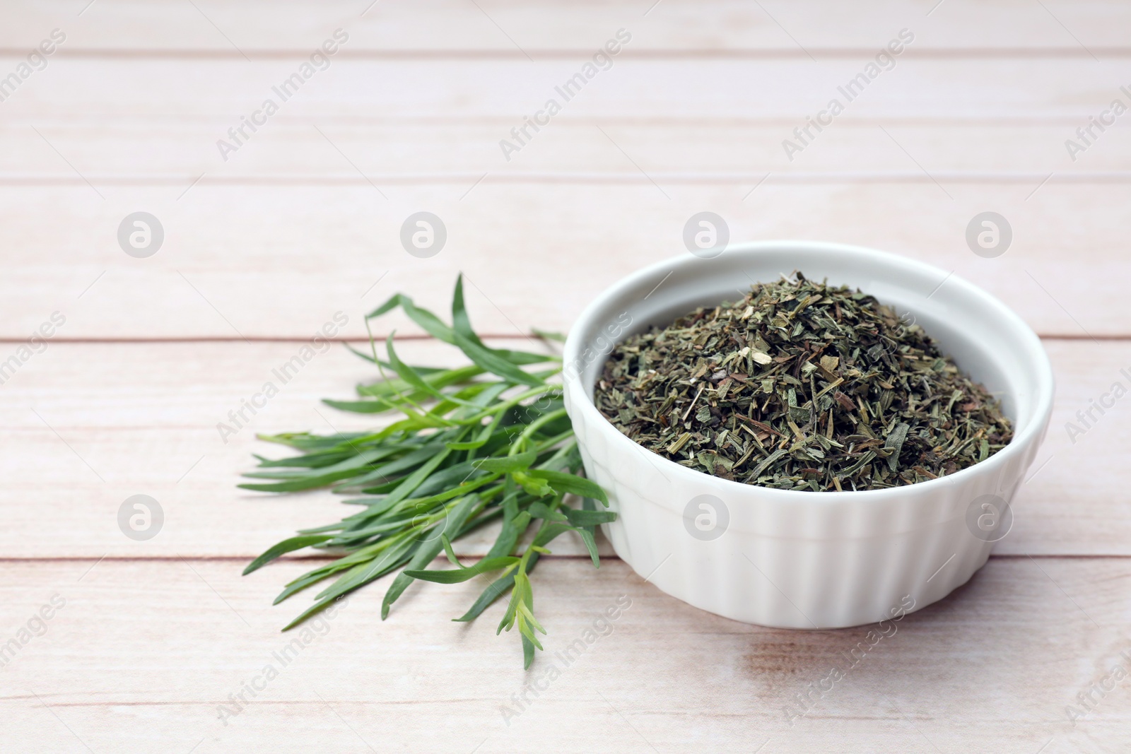 Photo of Dry and fresh tarragon on wooden table, space for text