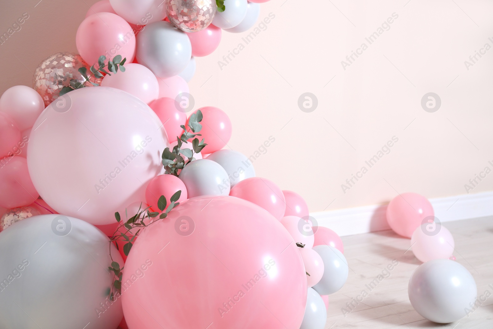 Photo of Beautiful composition with balloons and green leaves near beige wall