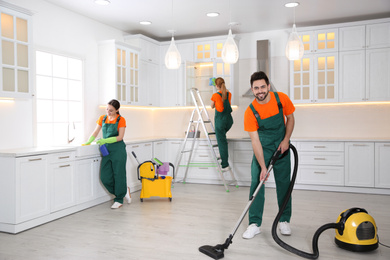 Team of professional janitors cleaning modern kitchen