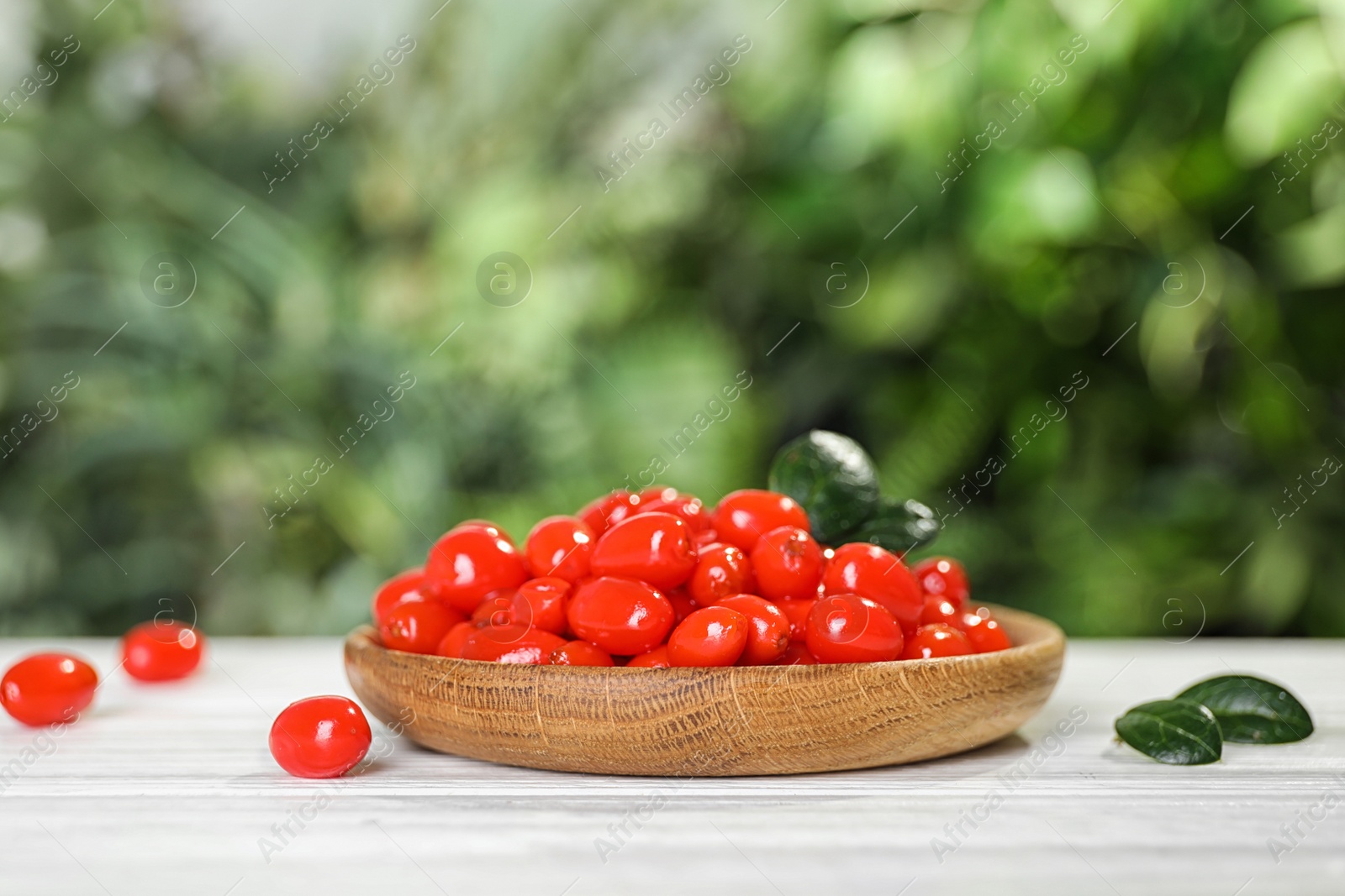 Photo of Plate with fresh goji berries on white wooden table against blurred background. Space for text