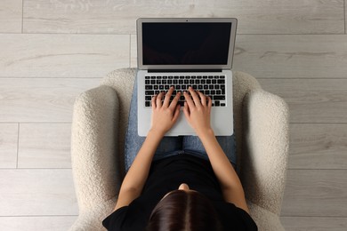 Woman working with laptop in armchair, top view