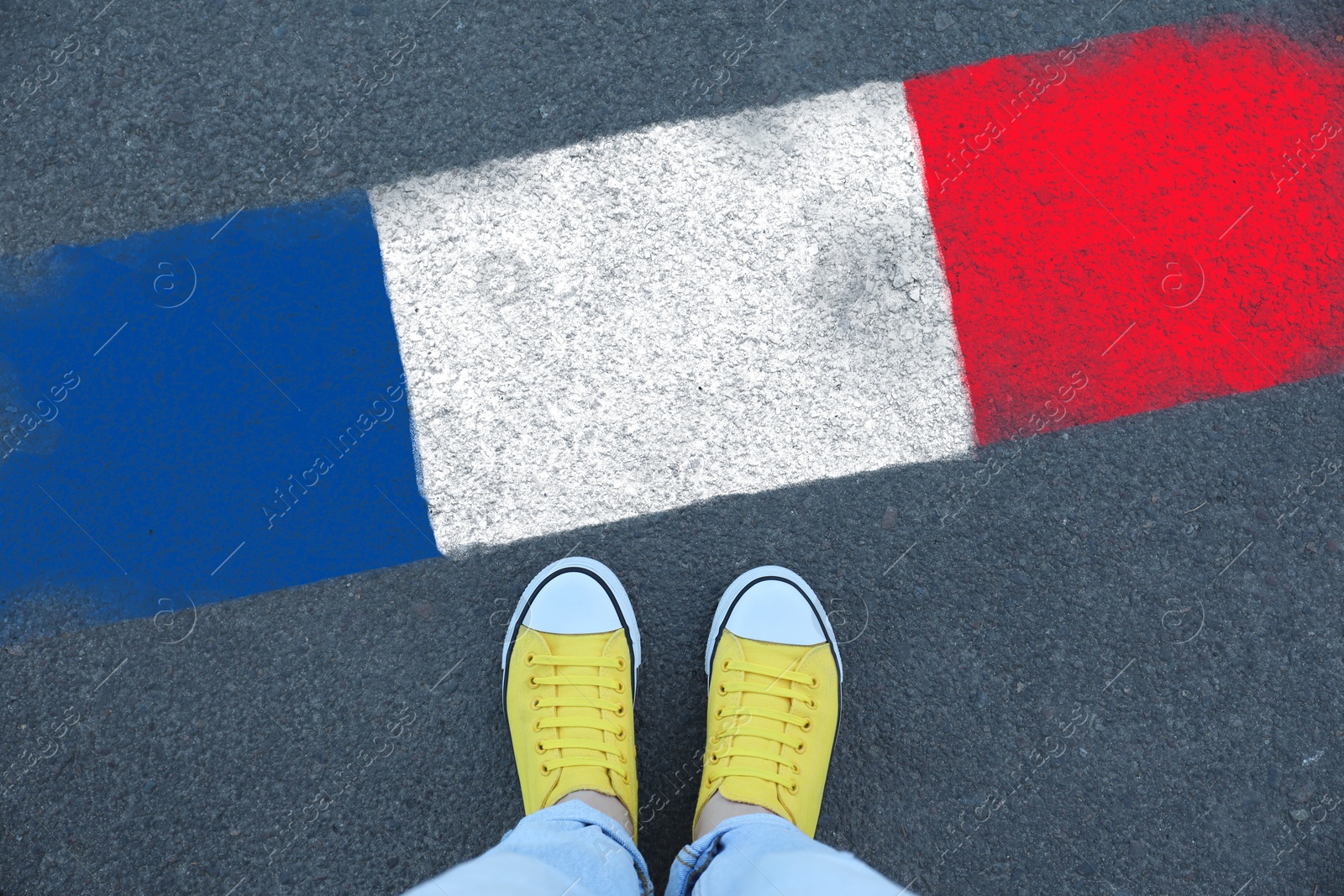 Image of Immigration. Woman standing on asphalt near flag of France, top view