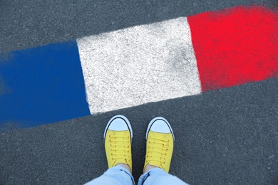 Image of Immigration. Woman standing on asphalt near flag of France, top view