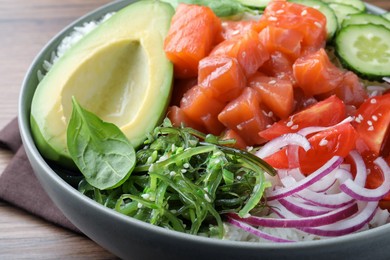 Delicious poke bowl with salmon and vegetables on table, closeup
