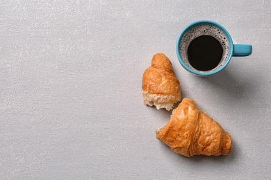 Photo of Tasty croissant and cup of coffee on light background, top view