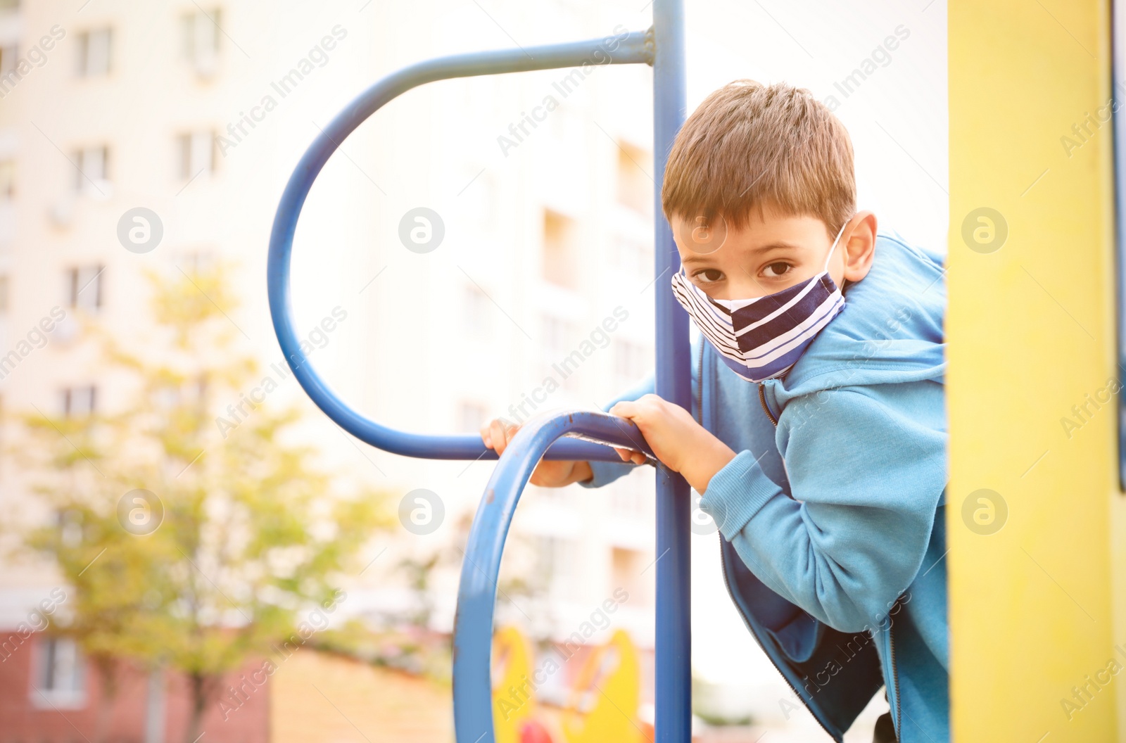 Photo of Little boy with medical face mask on playground during covid-19 quarantine
