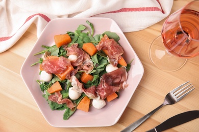 Photo of Flat lay composition of fresh melon with prosciutto on wooden table