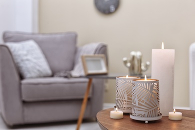 Photo of Burning candles on table indoors. Interior decor element