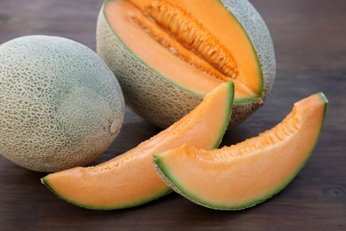 Photo of Whole and cut delicious ripe melons on wooden table, closeup