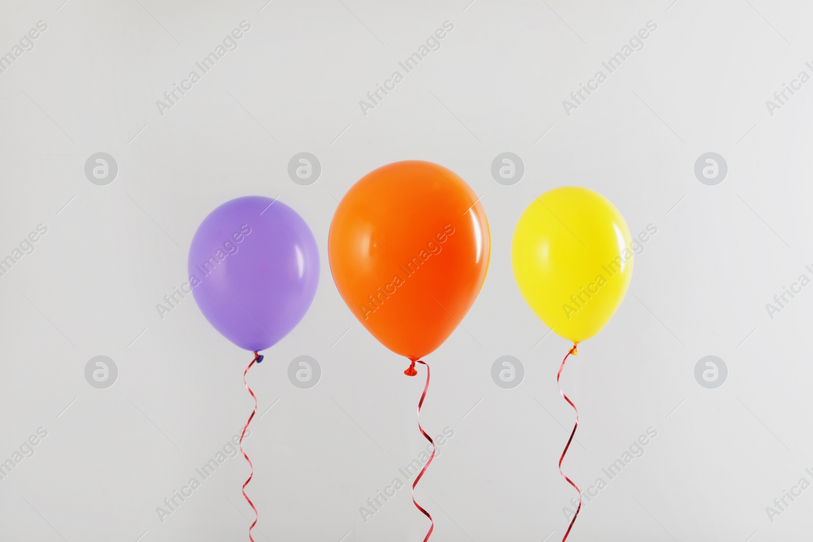 Photo of Different bright balloons on light background. Celebration time