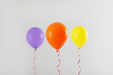 Photo of Different bright balloons on light background. Celebration time