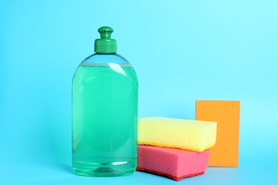 Photo of Detergent and sponges on light blue background