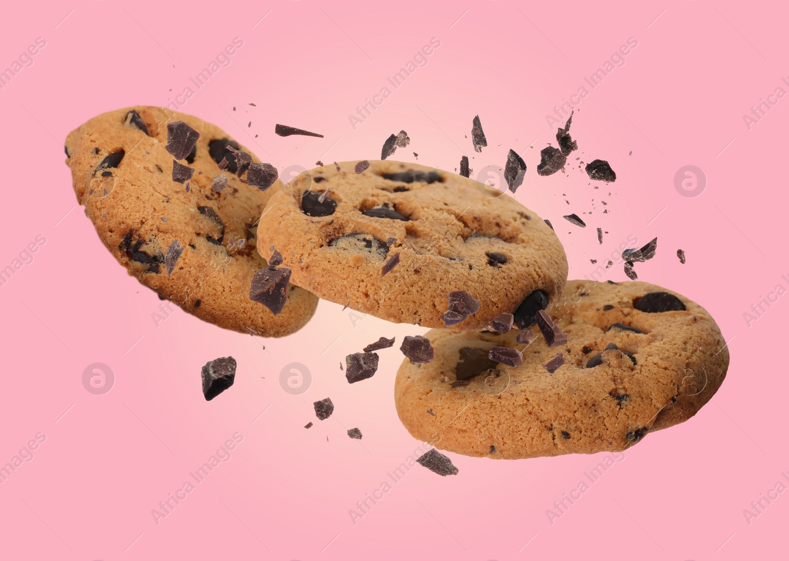 Image of Tasty chocolate chip cookies falling on pink background