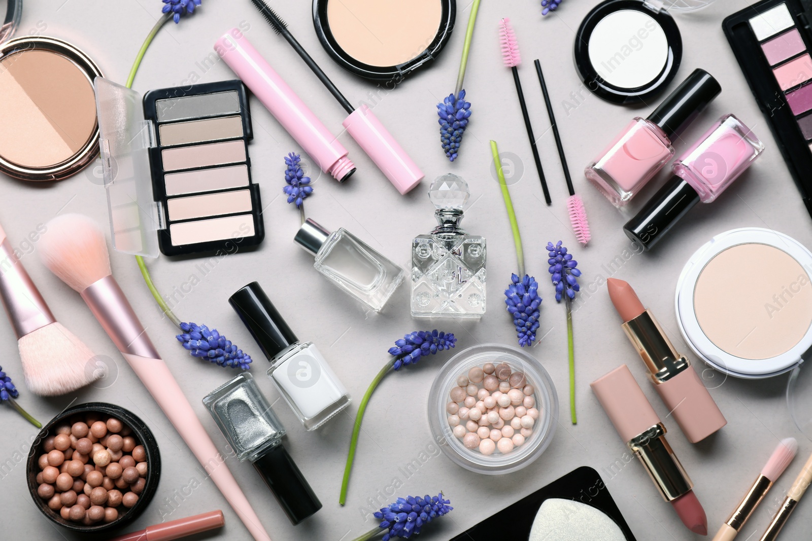 Photo of Flat lay composition with different makeup products and beautiful spring flowers on gray background