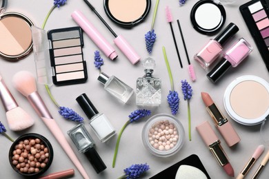 Flat lay composition with different makeup products and beautiful spring flowers on gray background