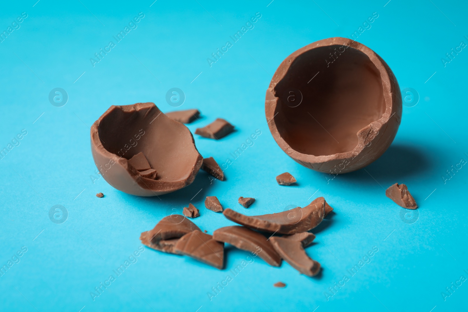 Photo of Broken chocolate egg on light blue background