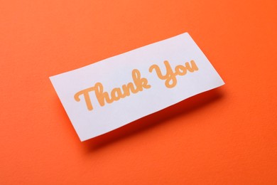 Photo of Note with phrase Thank You on orange background