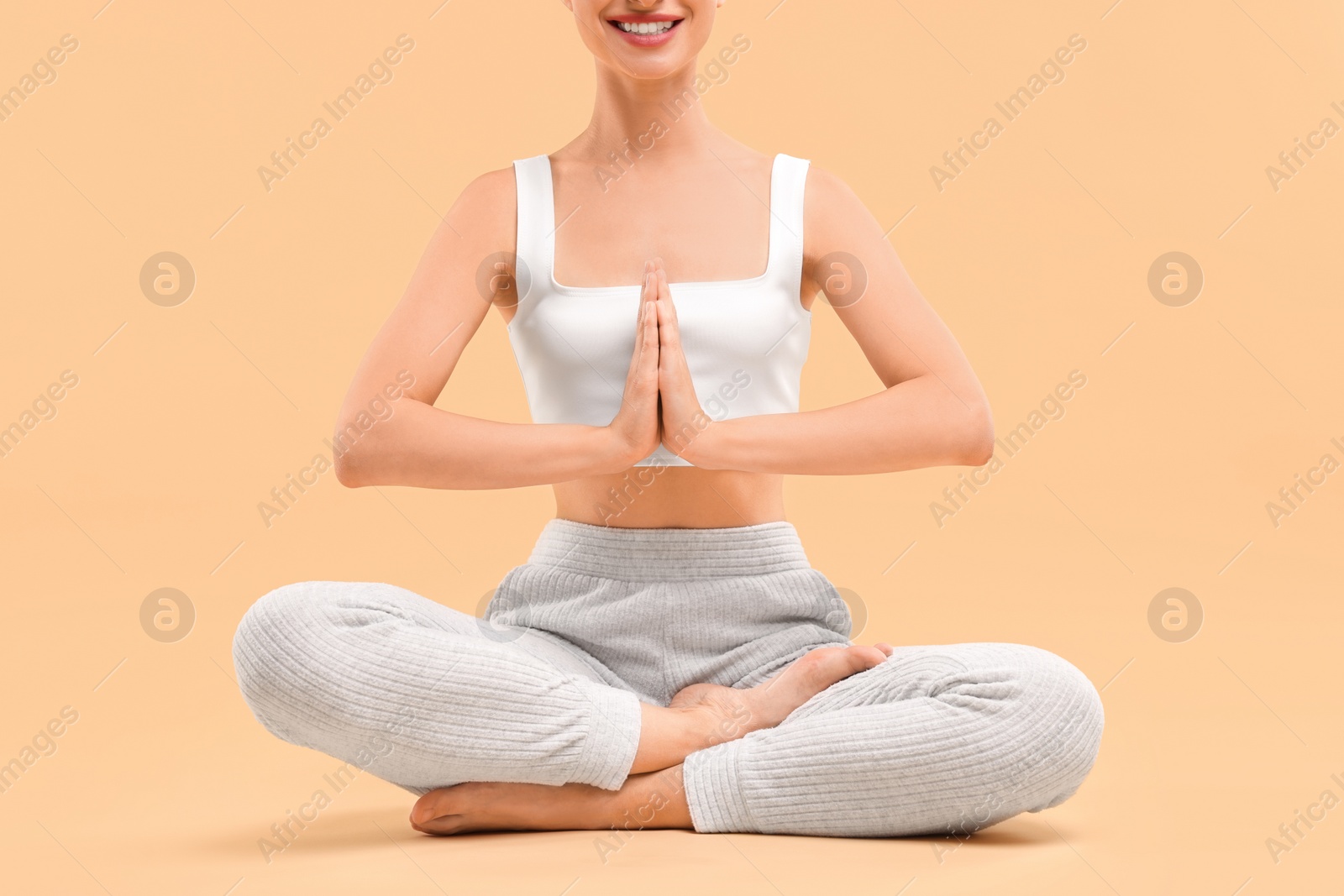 Photo of Woman practicing yoga on beige background, closeup. Lotus pose