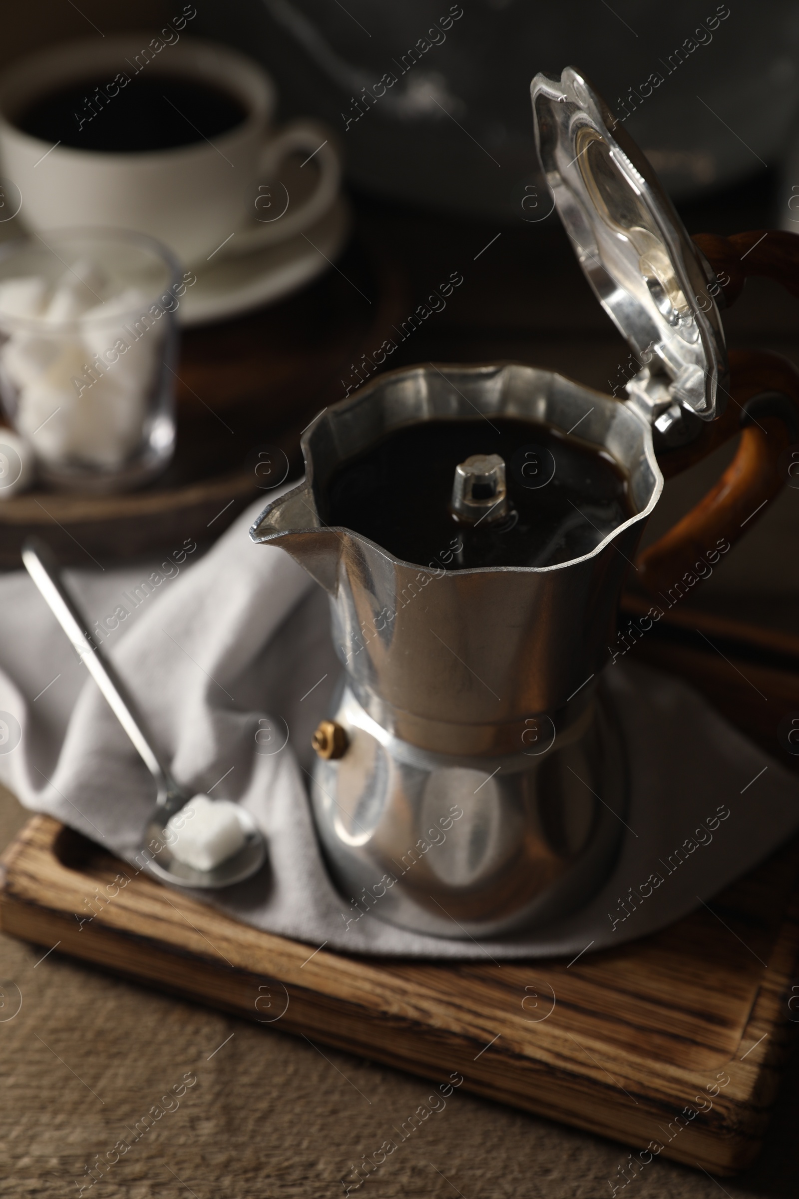 Photo of Brewed coffee in moka pot and sugar cube on wooden table