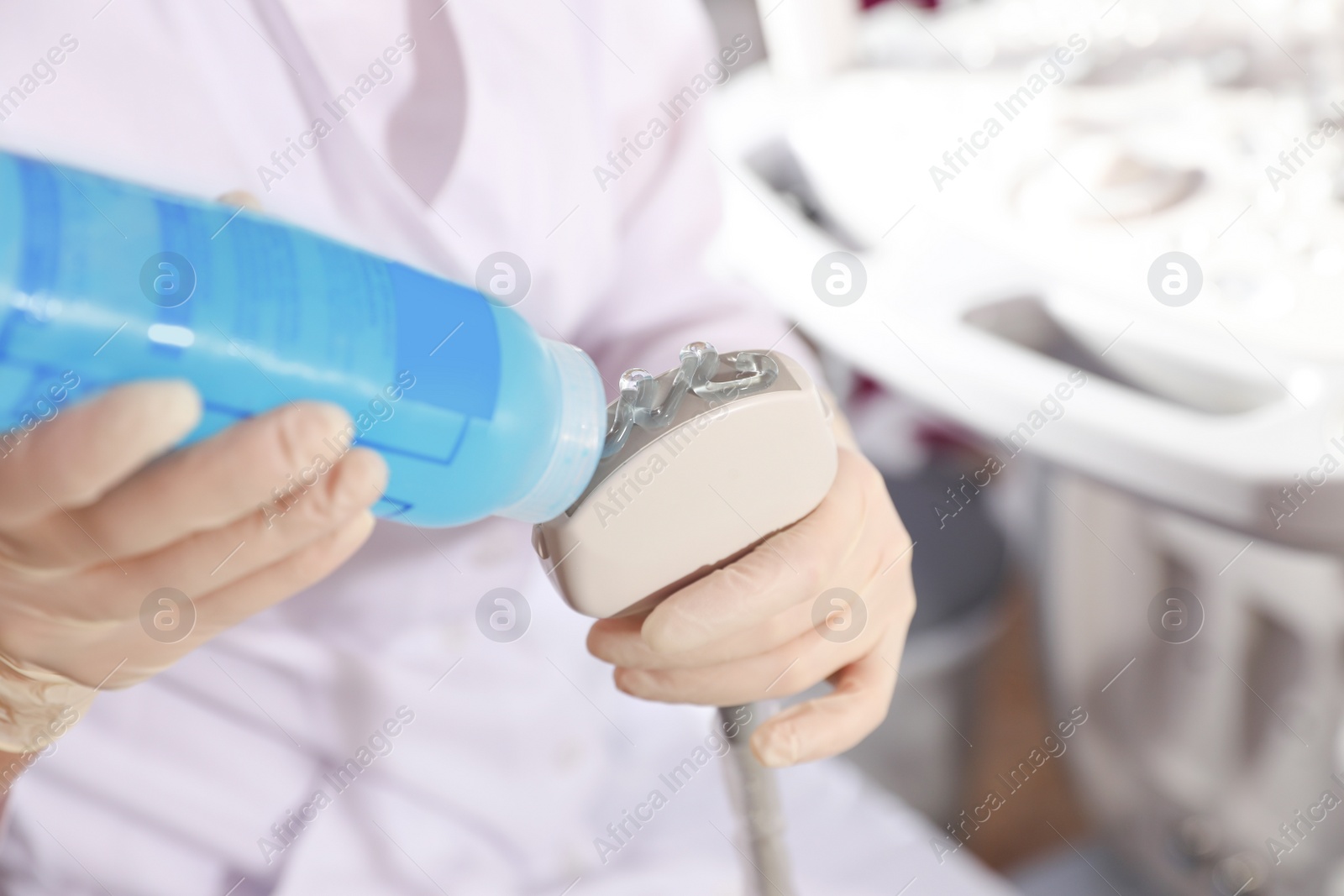 Photo of Sonographer covering ultrasound machine probe with gel in clinic, closeup