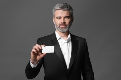 Photo of Handsome businessman holding blank business card on grey background