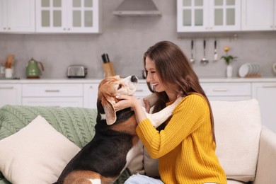 Photo of Happy young woman with her cute Beagle dog on couch at home. Lovely pet