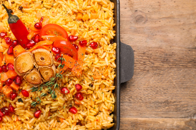 Photo of Tasty rice pilaf with vegetables on wooden table, top view