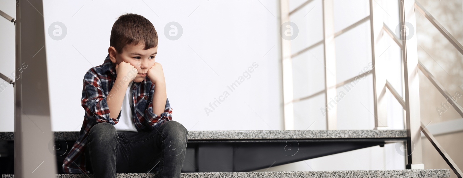 Image of Sad little boy sitting on stairs indoors, banner design with space for text. Time to visit child psychologist