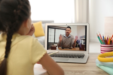 Photo of Distance learning, studying at home. Girl having online school lesson with teacher during quarantine and lockdown due to Covid-19 pandemic