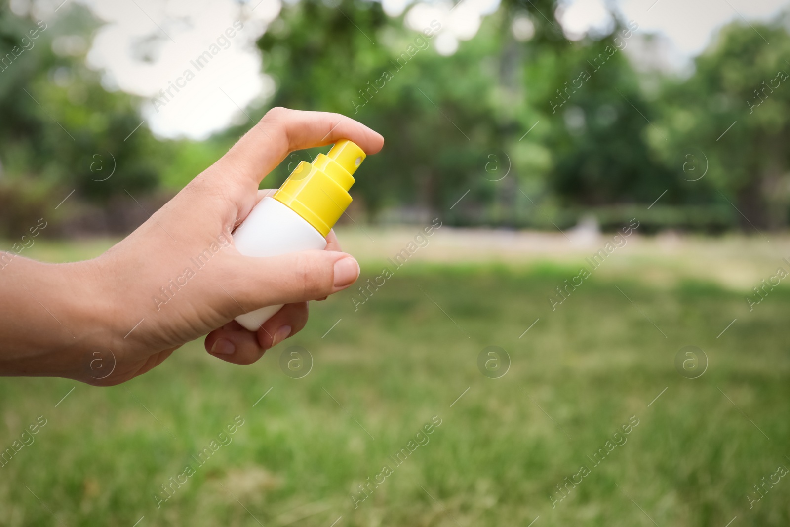 Photo of Woman with bottle of insect repellent spray outdoors, closeup