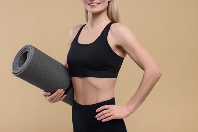 Photo of Athletic woman with fitness mat on beige background, closeup