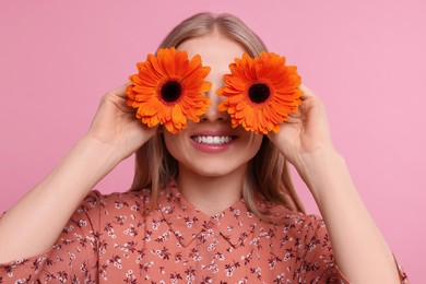 Photo of Woman covering her eyes with spring flowers on pink background