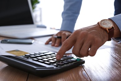 Photo of Tax accountant with calculator working at table in office, closeup