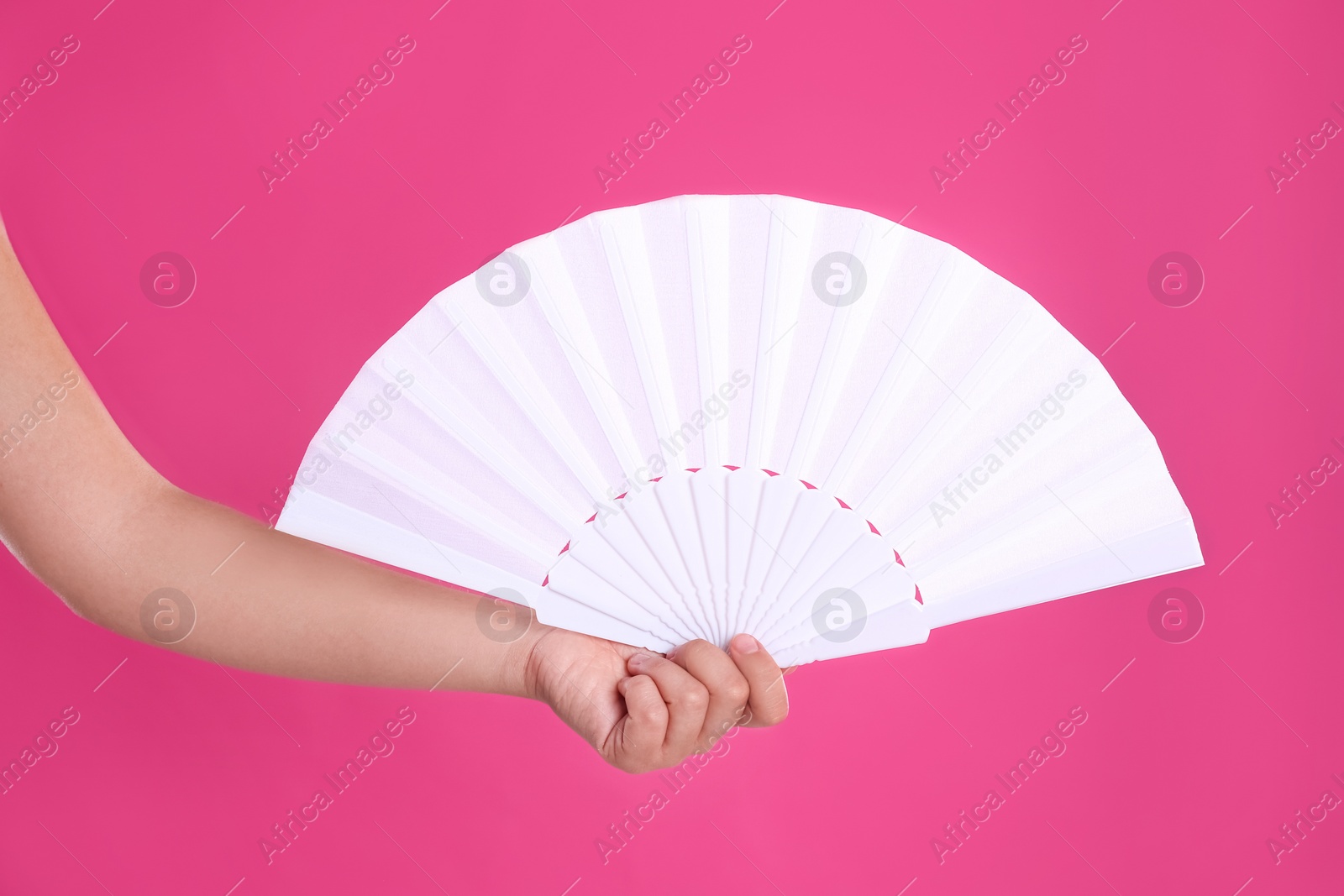 Photo of Woman holding white hand fan on pink background, closeup