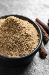 Photo of Liquorice powder in bowl on grey table, closeup