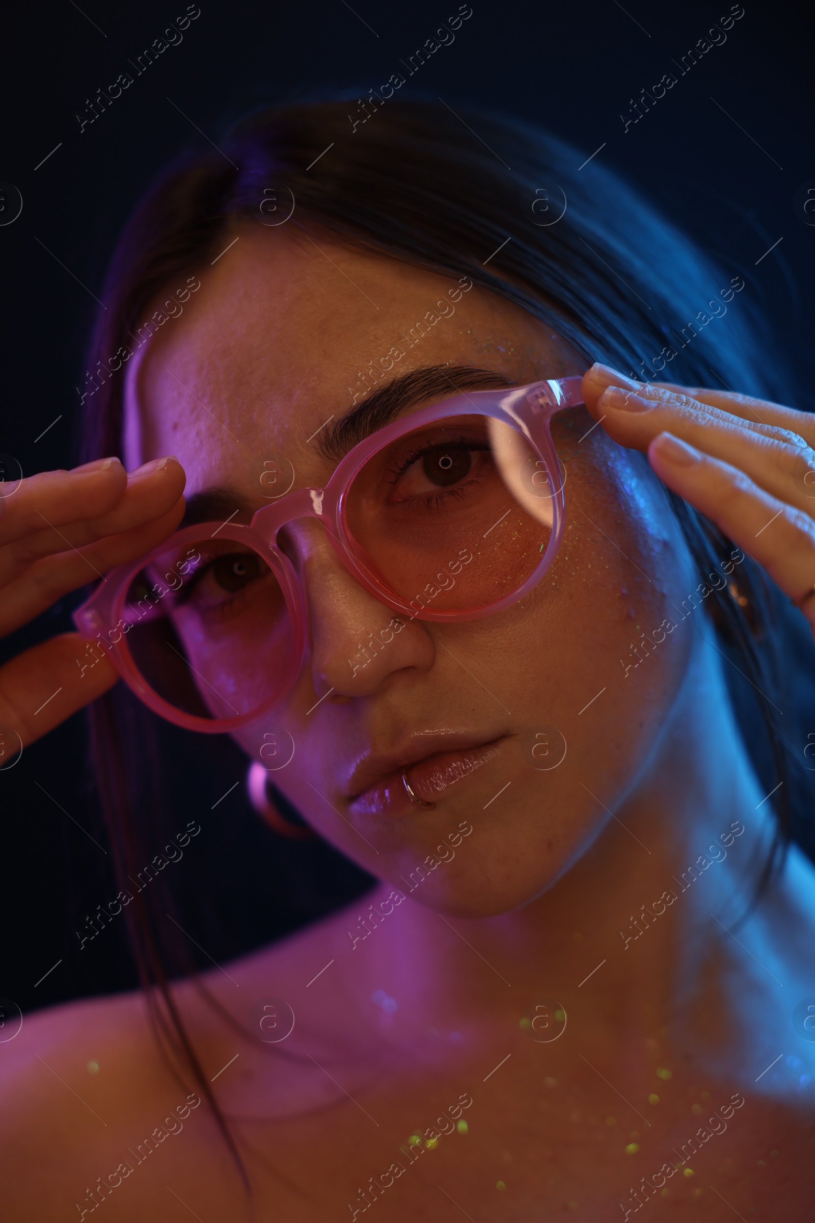 Photo of Beautiful woman in glasses on dark background in neon lights