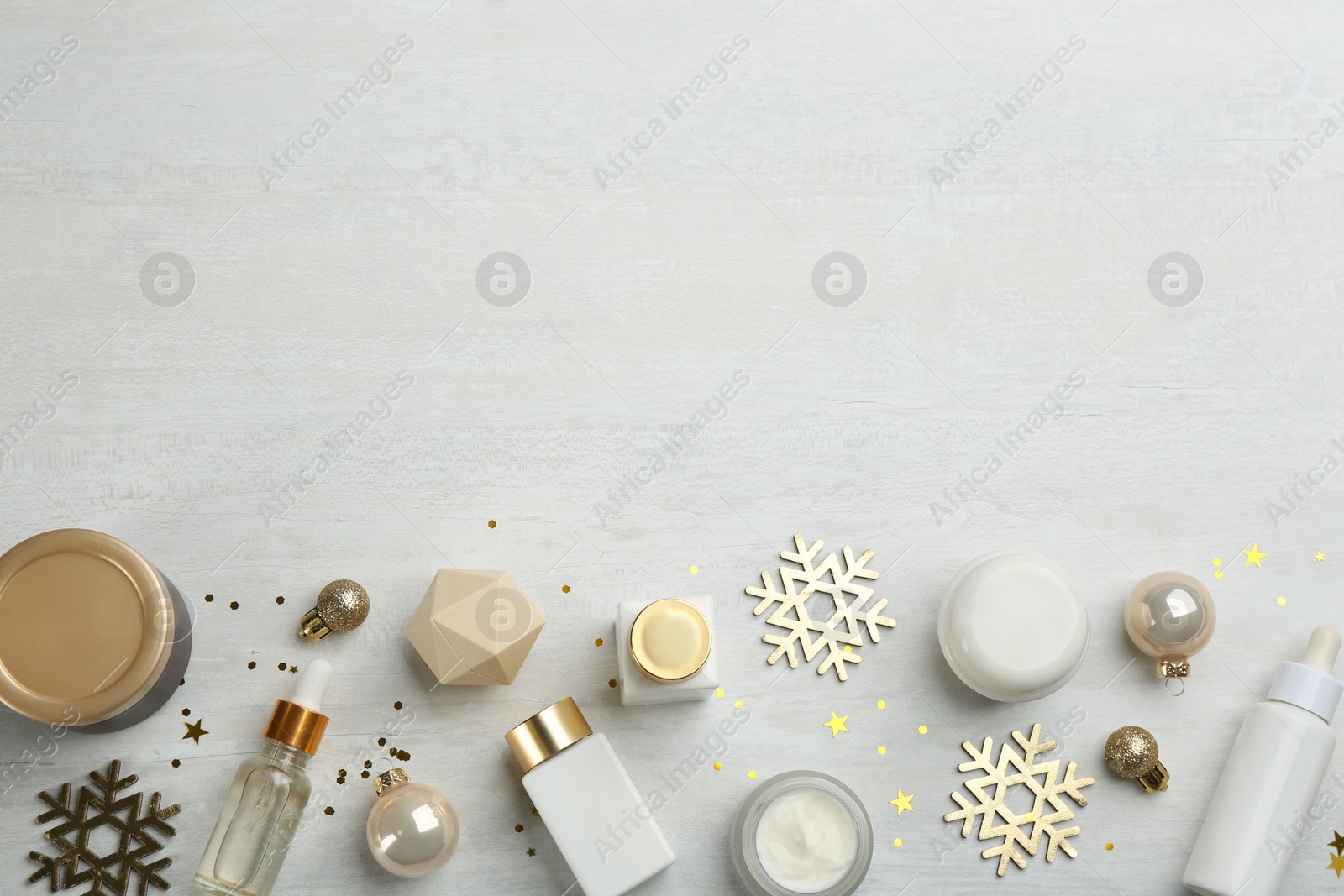 Photo of Flat lay composition with different cosmetic products on light table, space for text. Winter care
