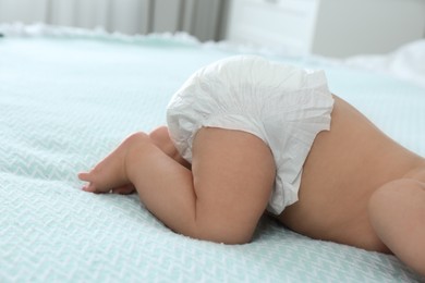 Cute little baby in diaper on bed at home, closeup