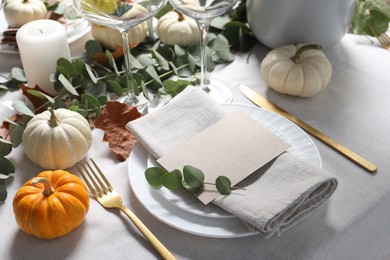 Photo of Beautiful autumn table setting. Plates, cutlery, glasses, blank card and floral decor