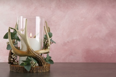 Photo of Burning candle in beautiful glass holder with eucalyptus on wooden table, space for text