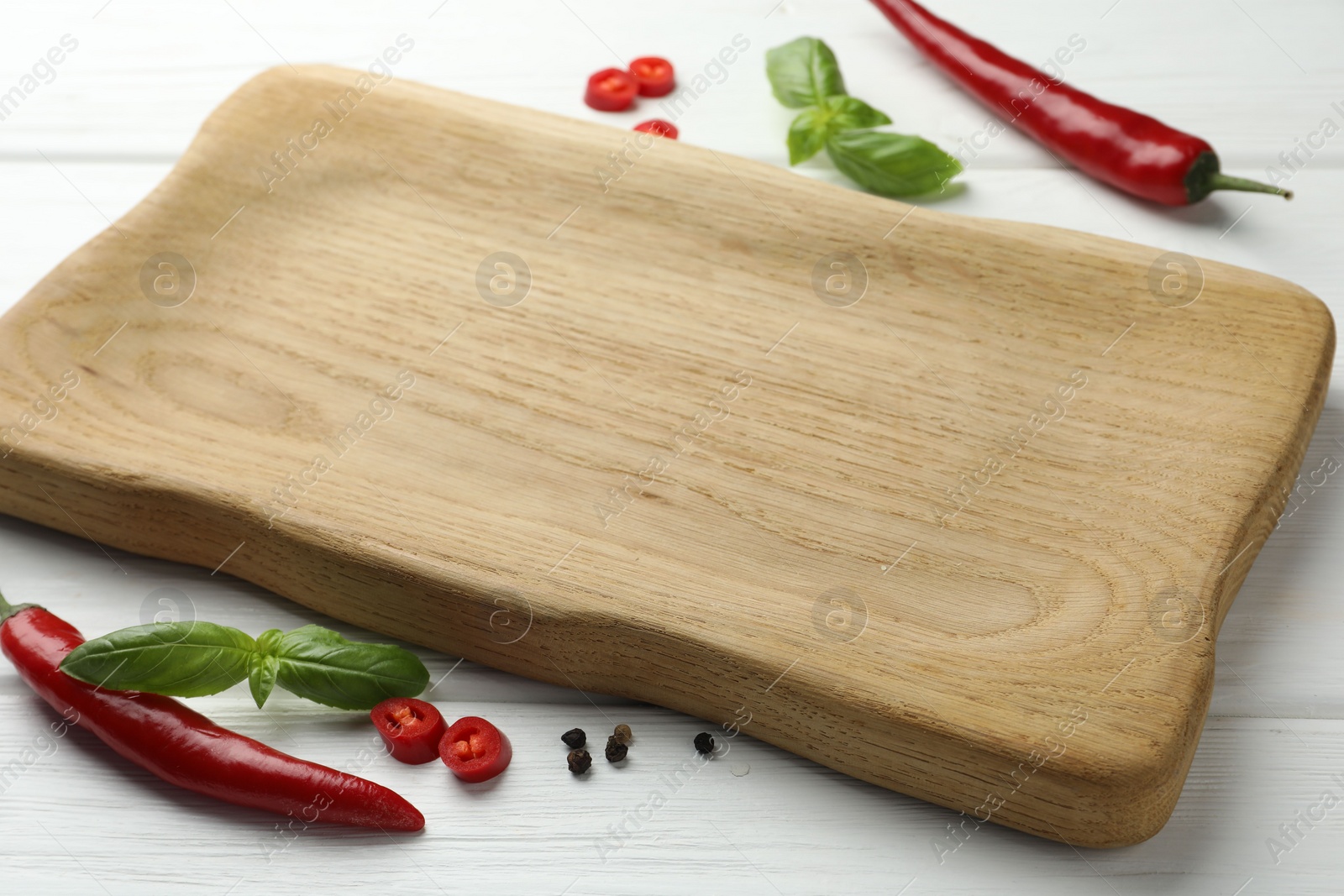 Photo of Cutting board and different spices on white wooden table