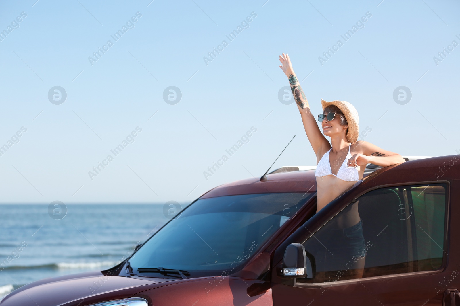 Photo of Young woman in straw hat near car on beach