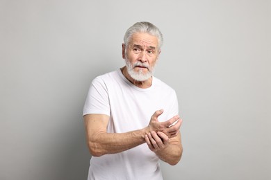 Photo of Arthritis symptoms. Man suffering from pain in wrist on gray background