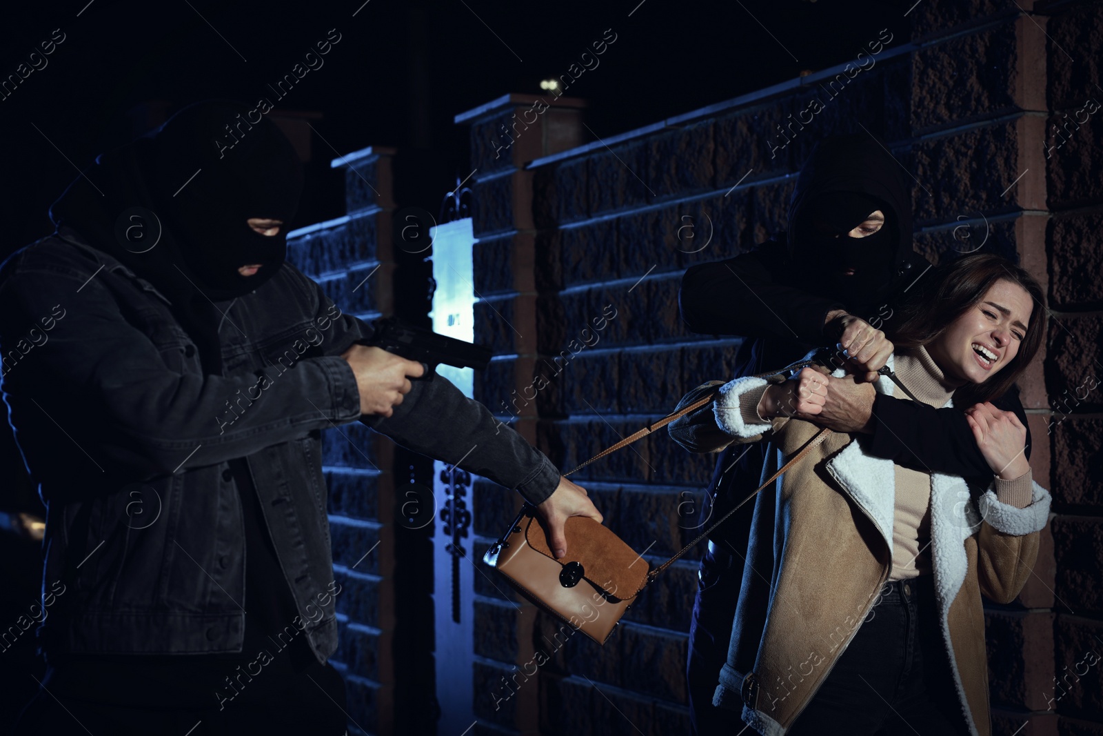 Photo of Thieves with weapons stealing woman's bag outdoors at night. Self defense concept