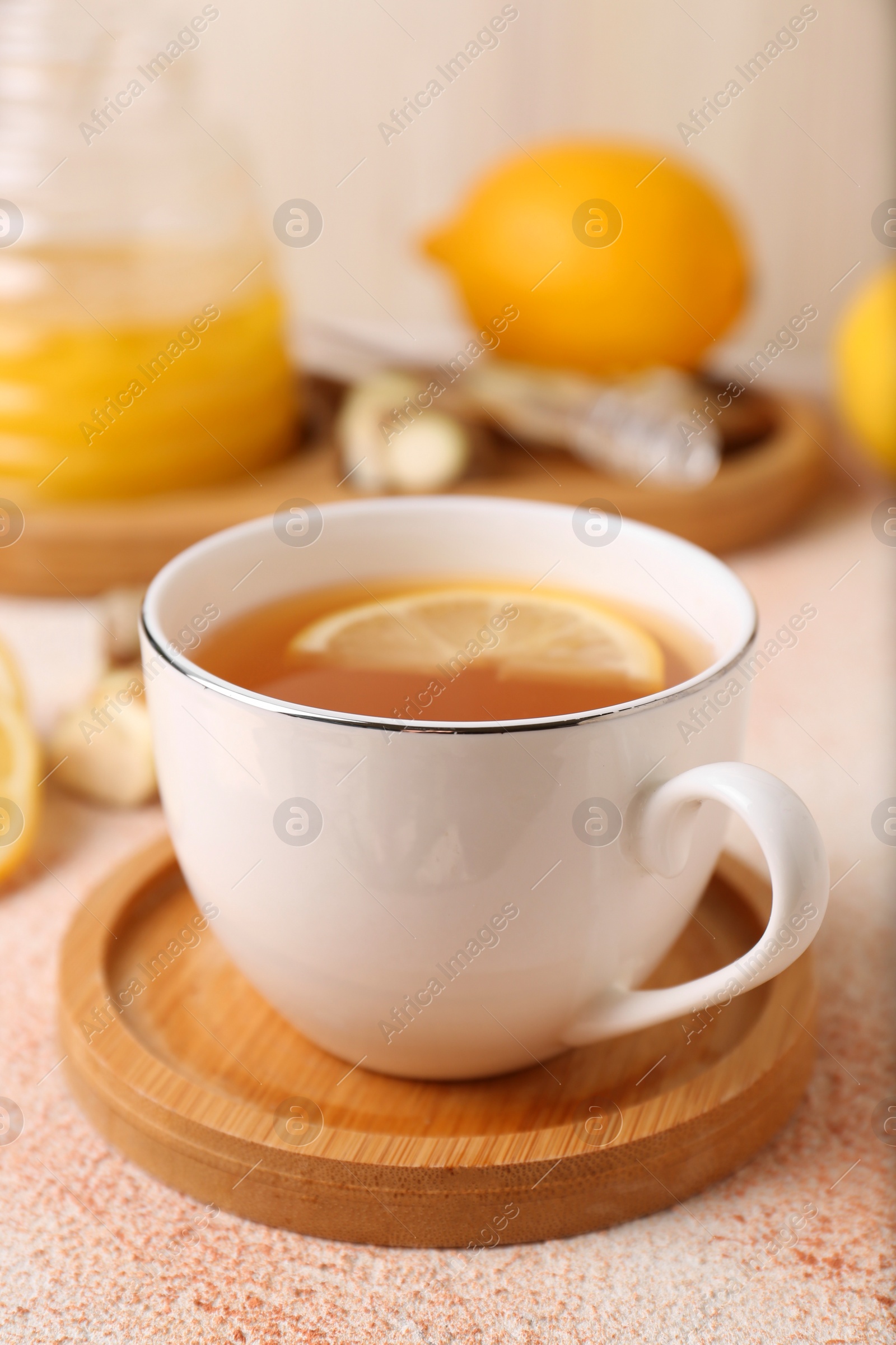 Photo of Tea, honey, lemon and ginger on beige textured table