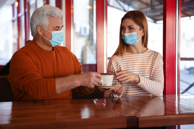 Photo of People with medical masks in cafe. Virus protection